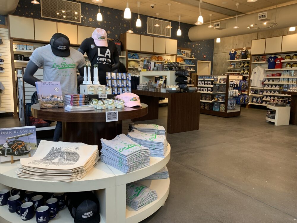 Stellar Emporium Gift Shop interior with shirts, mugs, and other items on display.
